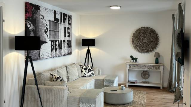 Modern eingerichtetes Apartment mit Sofa und Tisch Rema Homes