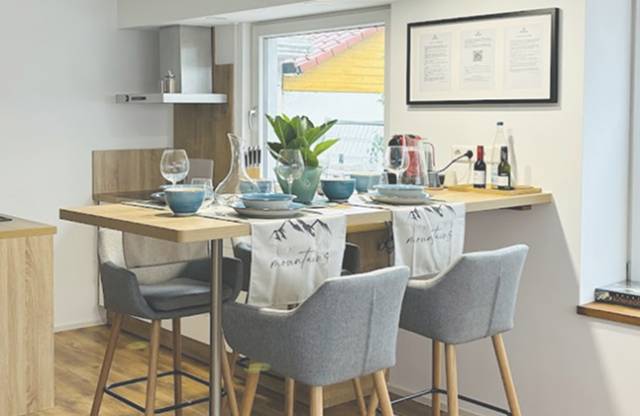 Bartisch mit grauen Barhockern Rema Homes Apartments