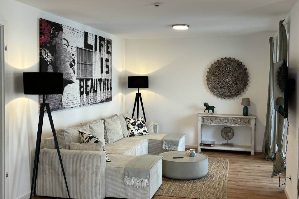 Modern eingerichtetes Apartment mit Sofa und Tisch Rema Homes